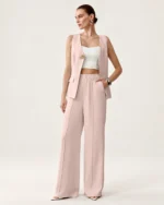 Modelo feminina vestindo conjunto de alfaiataria rosa blush com colete decote V e calça pantalona em estúdio mineral