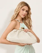 Bolsa Clutch Retrô com Fecho Kisslock em tom bege fendi segurada pela modelo.