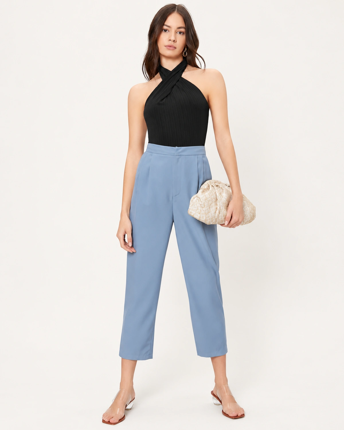 Modelo de corpo inteiro vestindo regata preta ajustada com decote halter cruzado e calça de alfaiataria.