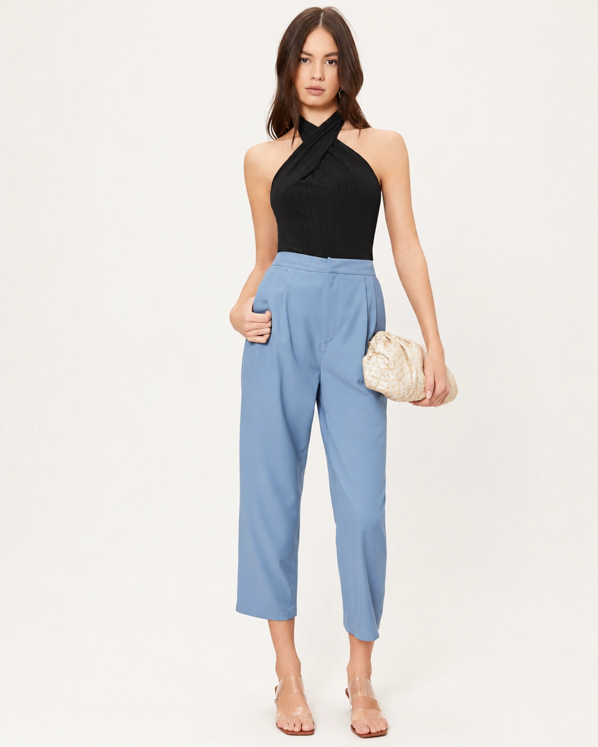 Foto de corpo inteiro da modelo combinando regata halter preta com calça alfaiataria e bolsa clutch.