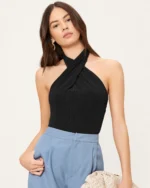 Plano médio editorial da modelo com postura angulada vestindo regata halter preta.