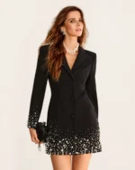 Plano americano da modelo com vestido blazer preto, colar de pérolas e clutch de festa.