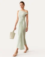 Modelo em movimento de passo com vestido midi assimétrico verde-menta e sobressaia plissada