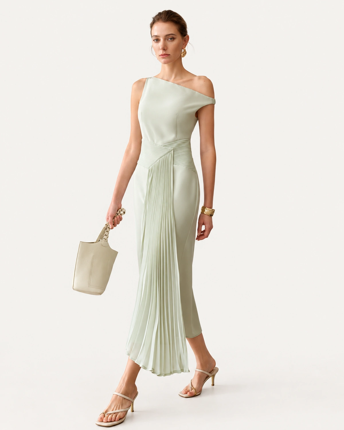 Modelo em movimento de passo com vestido midi assimétrico verde-menta e sobressaia plissada