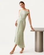 Modelo posando ao lado de balcão minimalista vestindo vestido midi assimétrico verde-menta