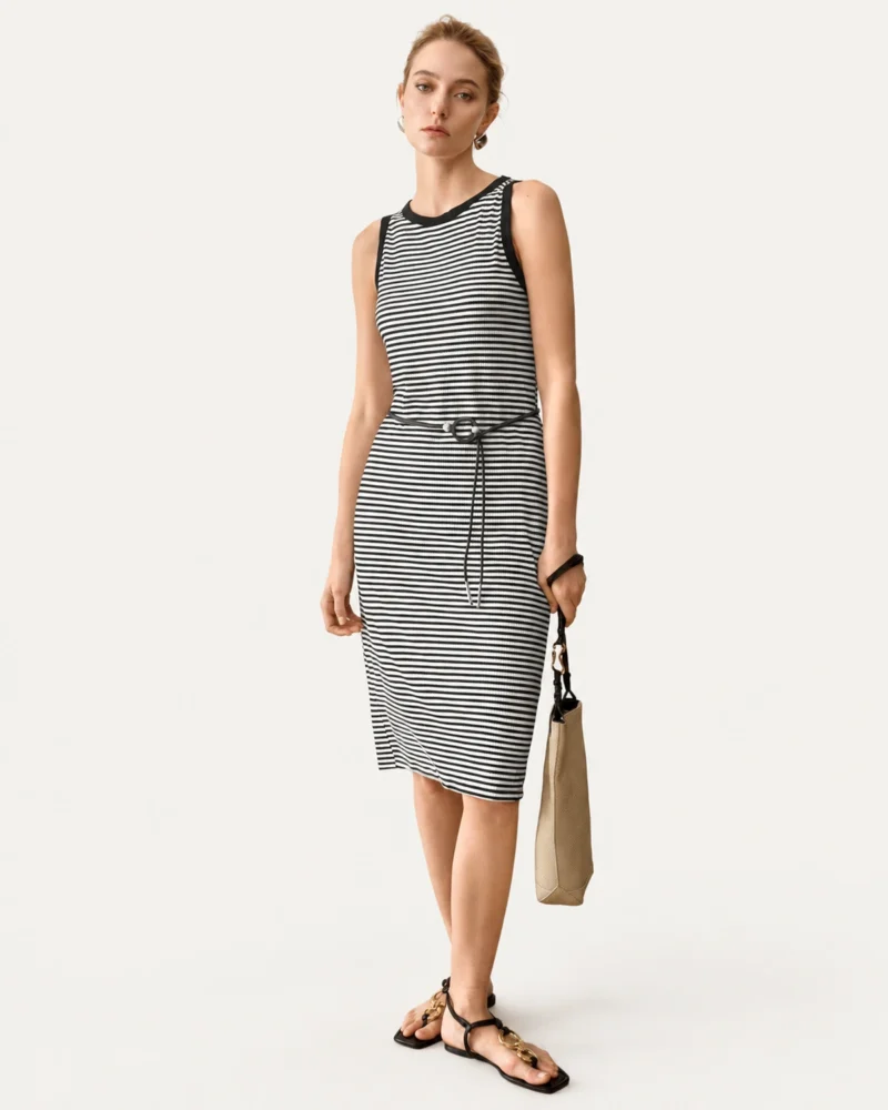 Vestido midi listrado preto e branco com cinto fino visto de frente em modelo
