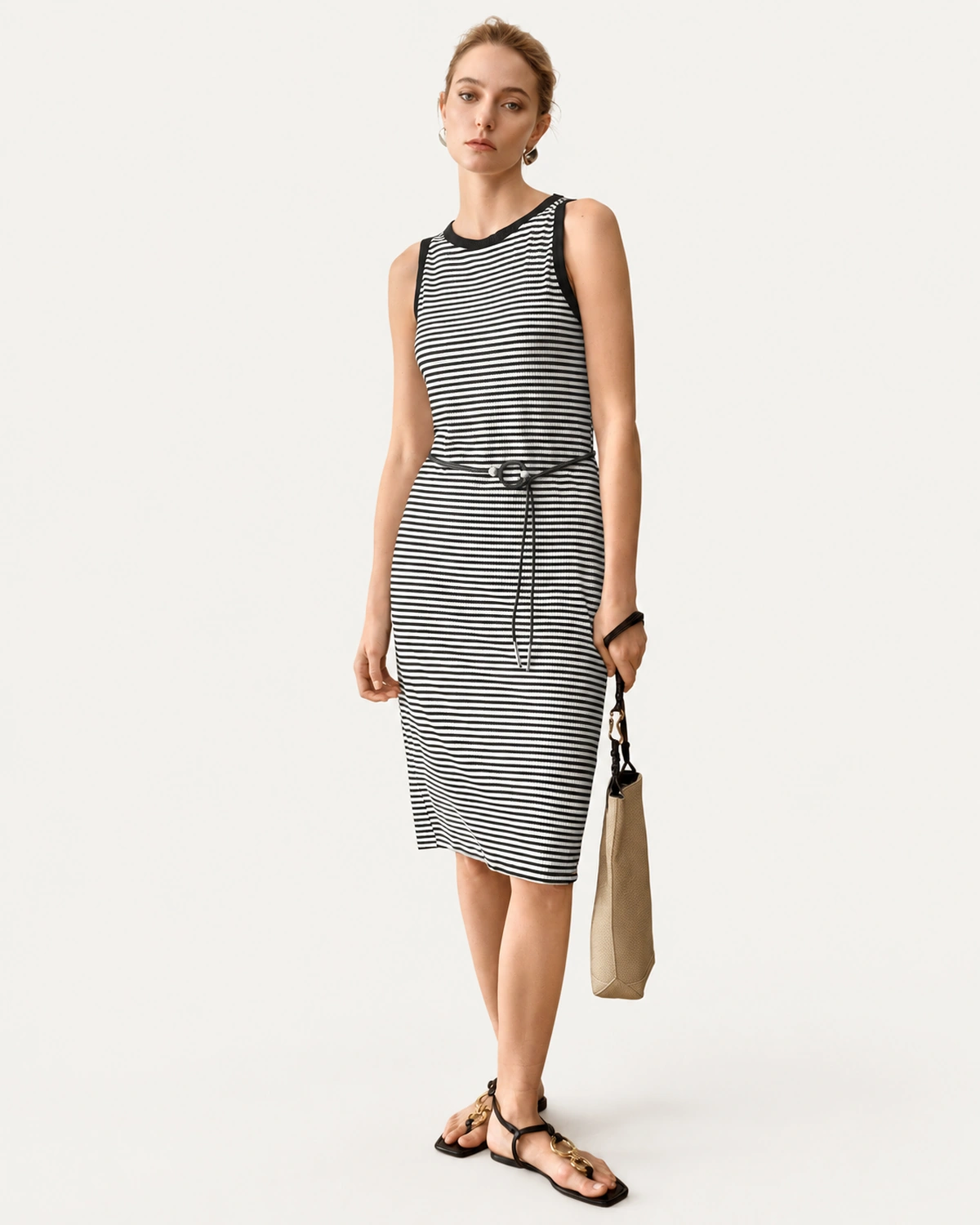 Vestido midi listrado preto e branco com cinto fino visto de frente em modelo