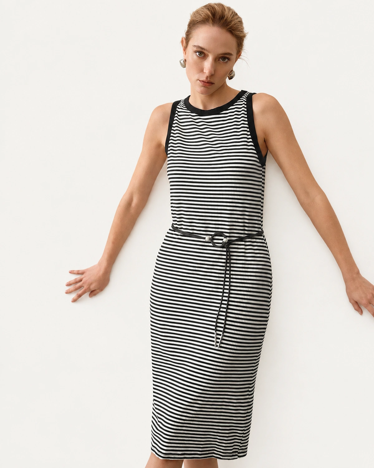 Modelo posando com vestido midi listrado preto e branco com decote contrastante