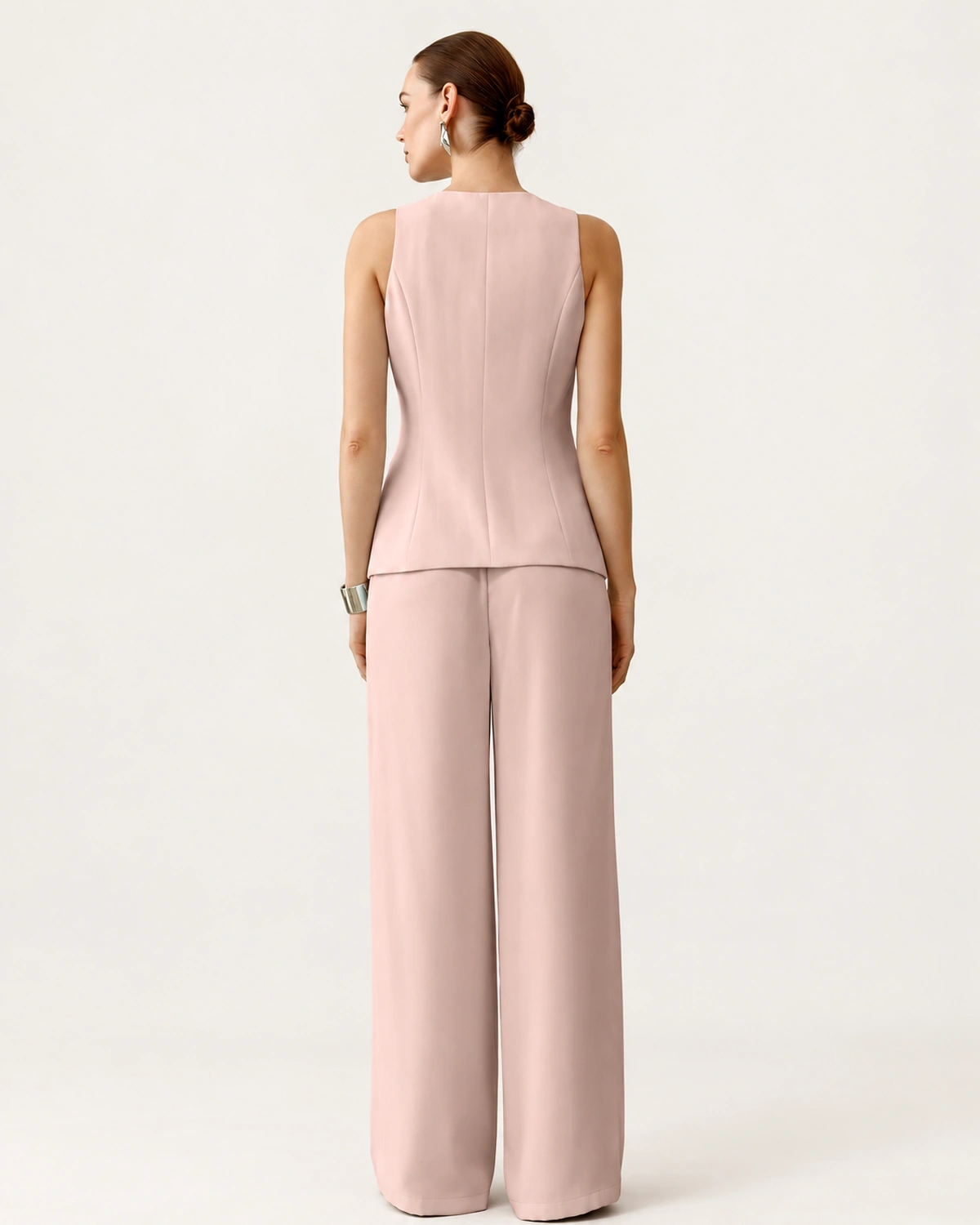 Vista posterior de costas da modelo vestindo o conjunto de alfaiataria rosa blush em estúdio mineral