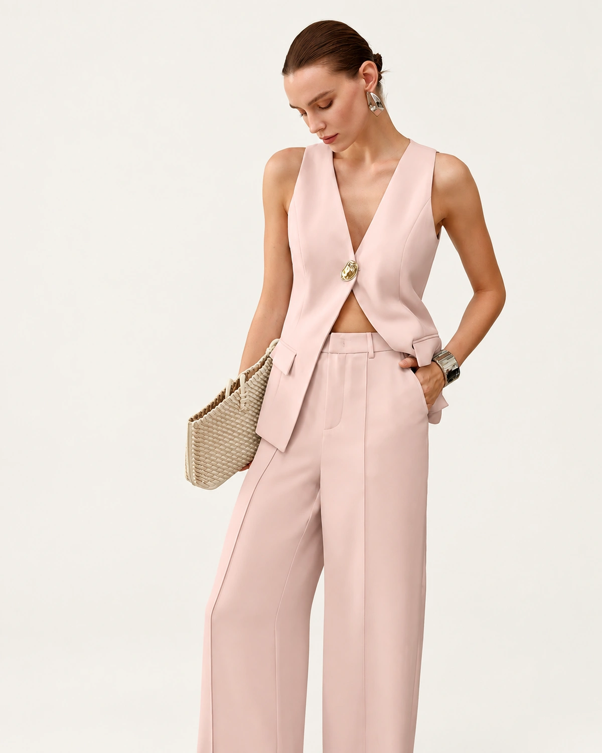 Modelo em plano três quartos com conjunto de alfaiataria rosa blush e bolsa tote trançada off-white