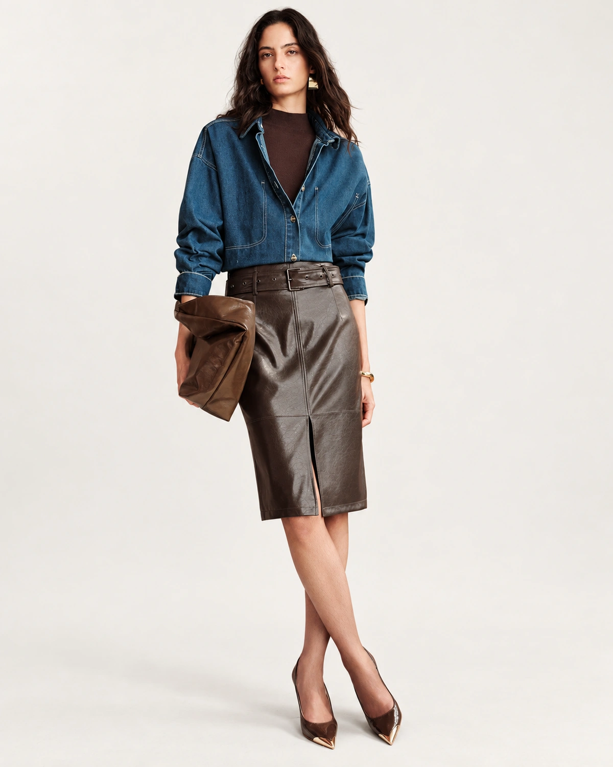 Plano inteiro da modelo vestindo look completo com saia de couro marrom em estúdio mineral
