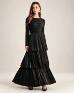 Modelo vestindo vestido longo preto acetinado com saia em três camadas plissadas em estúdio mineral