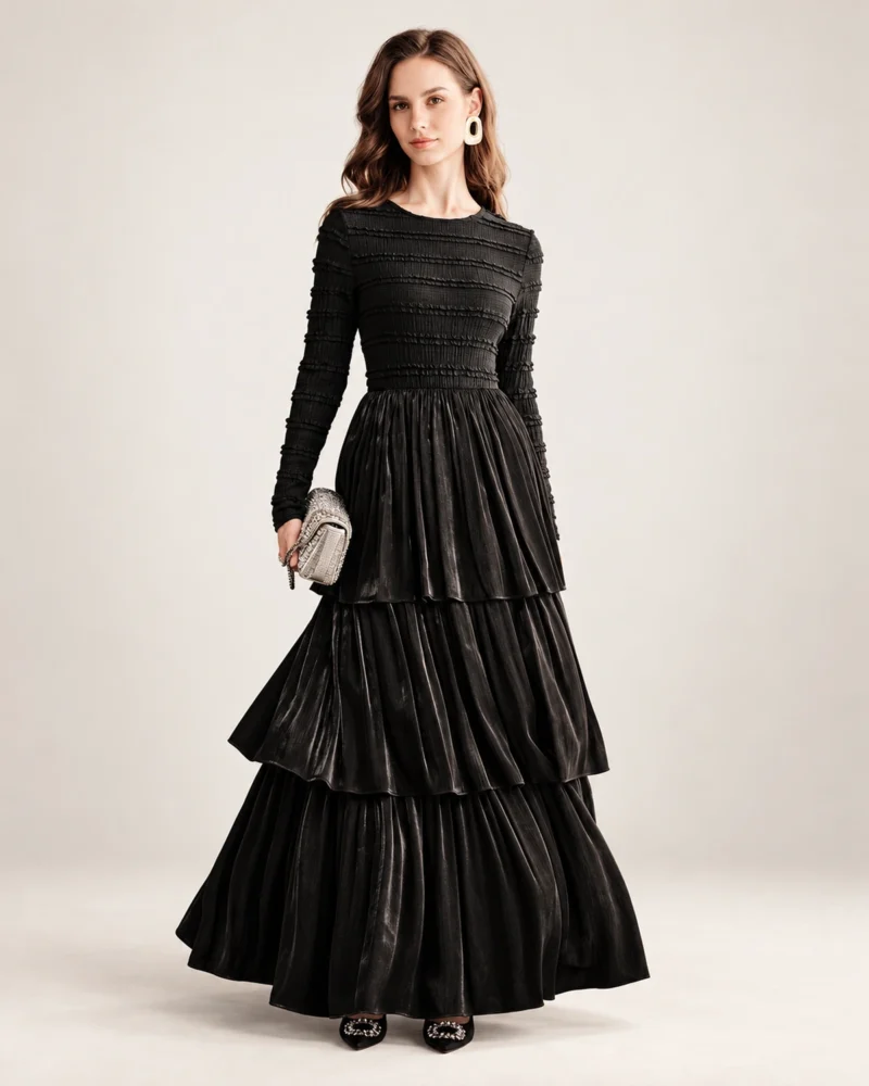 Modelo vestindo vestido longo preto acetinado com saia em três camadas plissadas em estúdio mineral