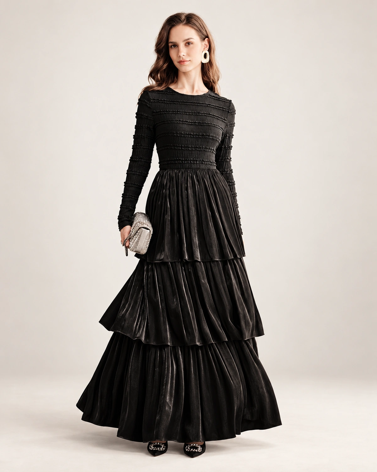 Modelo vestindo vestido longo preto acetinado com saia em três camadas plissadas em estúdio mineral