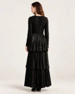 Modelo vestindo vestido longo preto acetinado com saia em três camadas plissadas em estúdio mineral