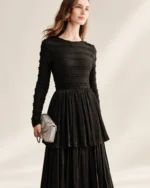 Modelo vestindo vestido longo preto acetinado com saia em três camadas plissadas em estúdio mineral