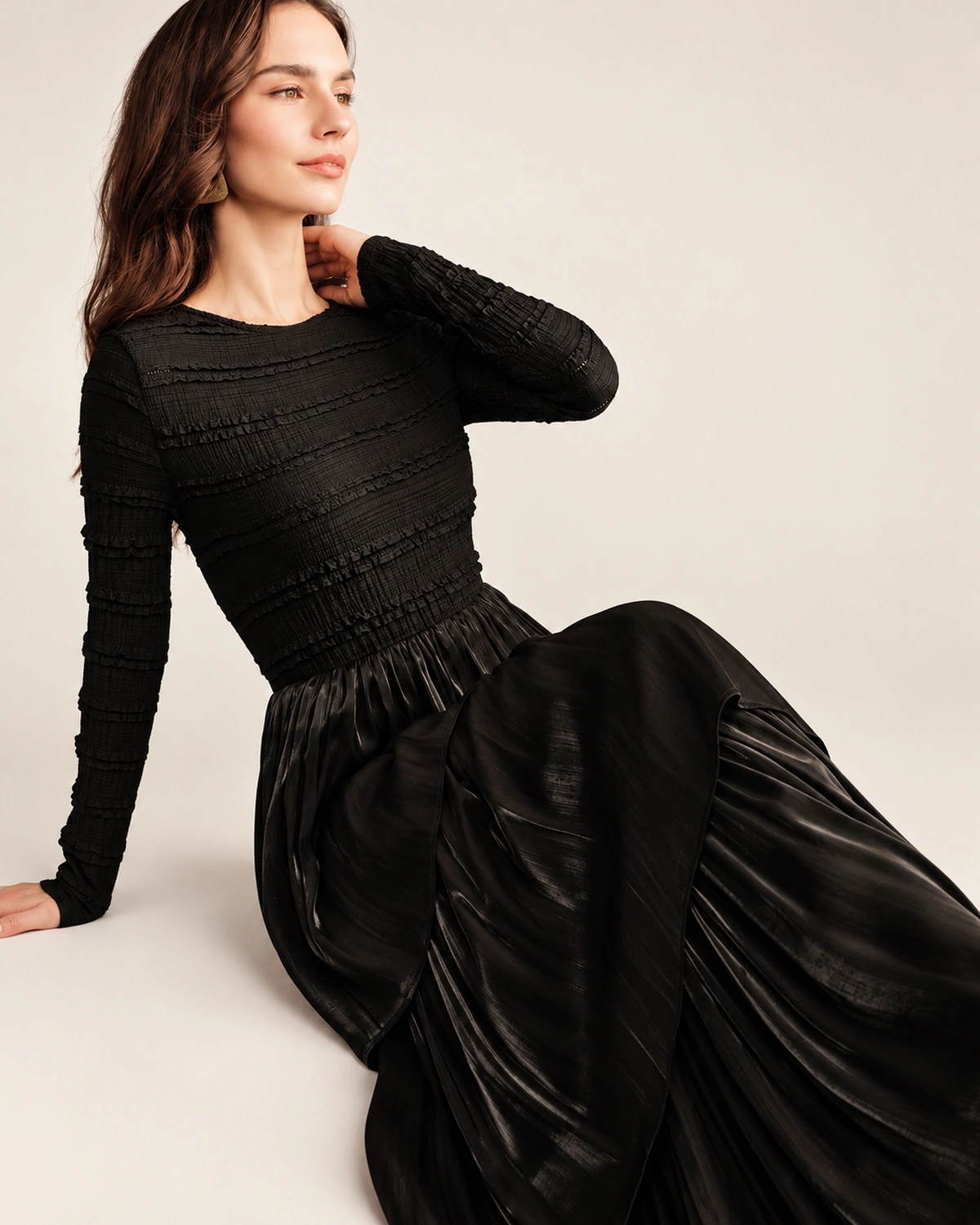 Modelo vestindo vestido longo preto acetinado com saia em três camadas plissadas em estúdio mineral