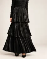 Modelo vestindo vestido longo preto acetinado com saia em três camadas plissadas em estúdio mineral