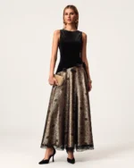 Plano inteiro da modelo vestindo vestido longo de veludo e renda com clutch em estúdio mineral.
