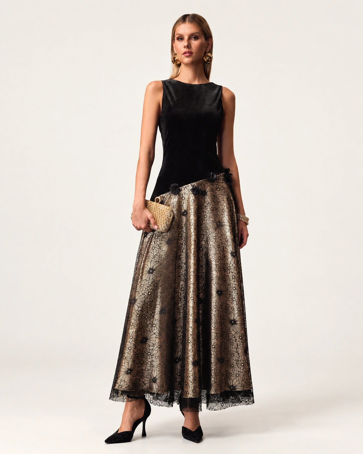 Plano inteiro da modelo vestindo vestido longo de veludo e renda com clutch em estúdio mineral.
