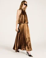 Plano dinâmico da modelo vestindo vestido fluido em cetim bronze em estúdio mineral