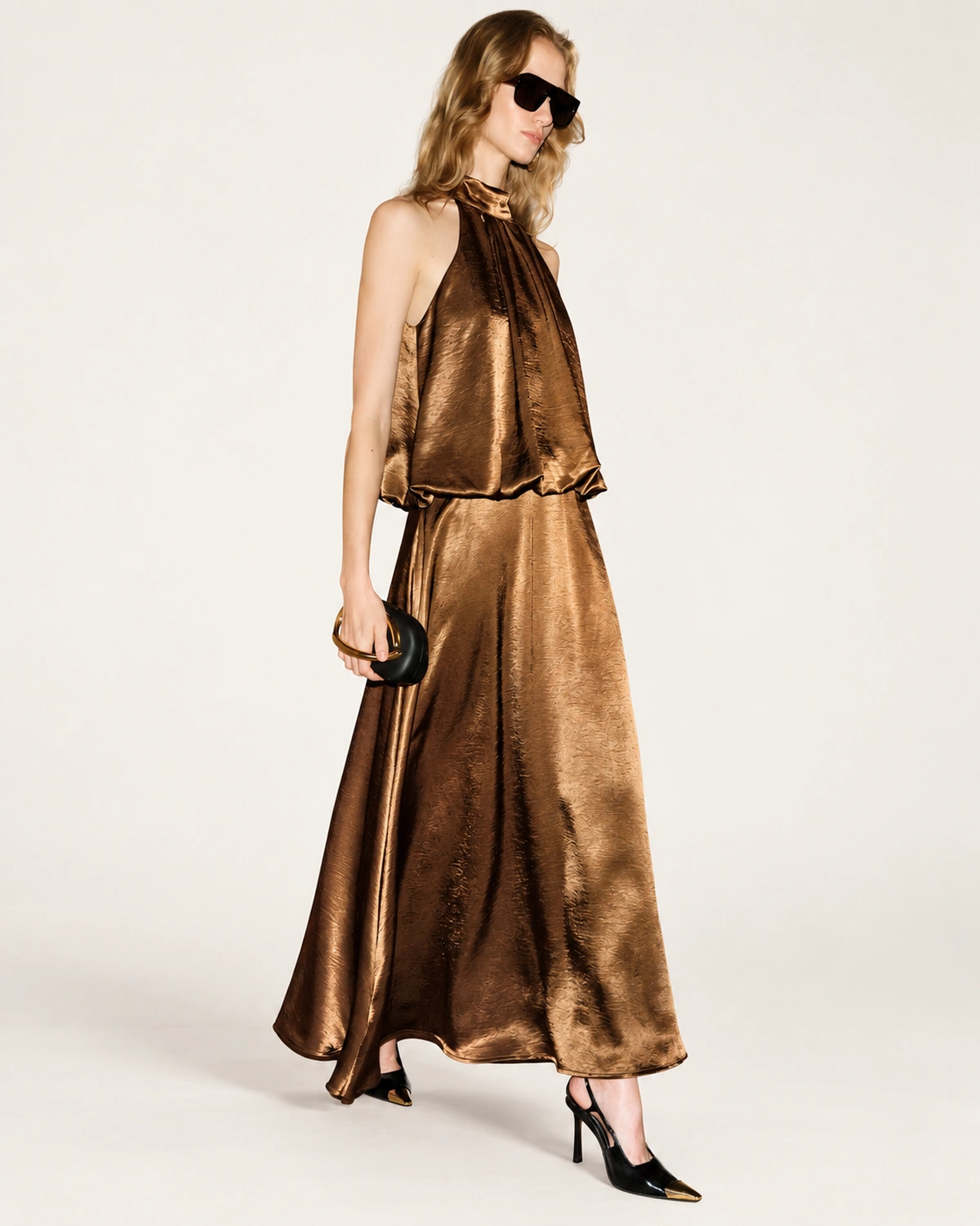Plano dinâmico da modelo vestindo vestido fluido em cetim bronze em estúdio mineral