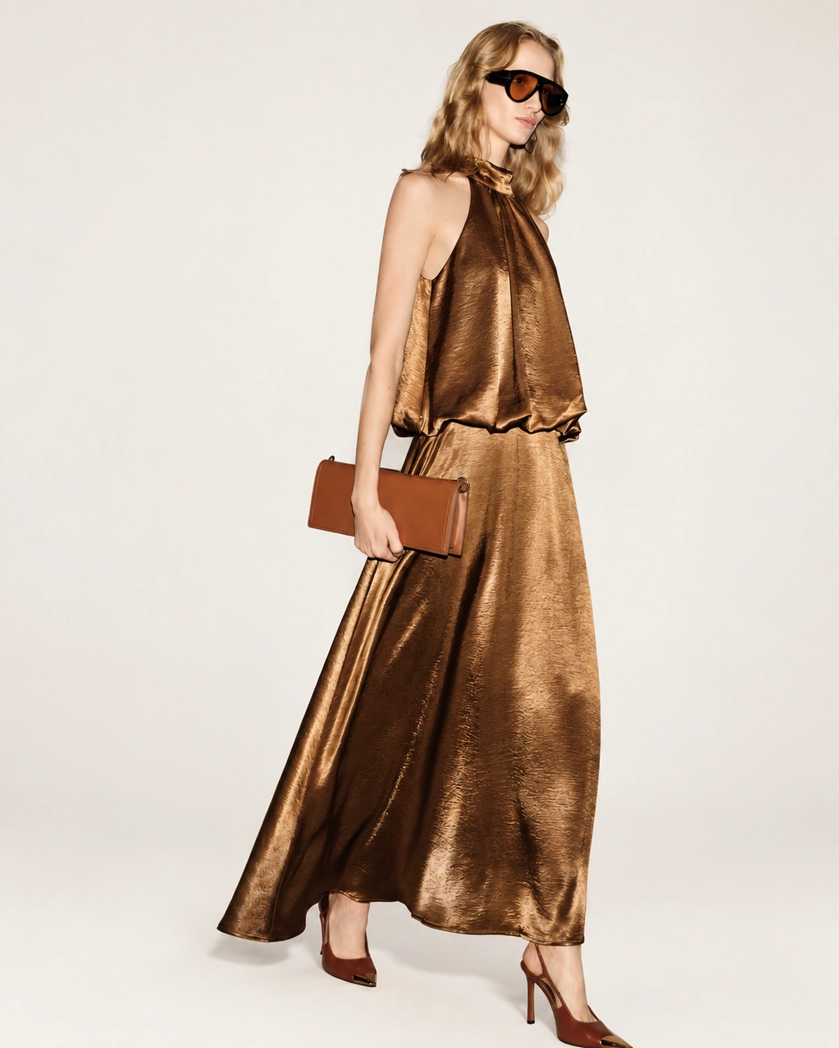 Plano americano da modelo com clutch e vestido em cetim bronze