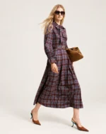 Passada dinâmica da modelo vestindo vestido longo plissado xadrez com bolsa em estúdio mineral