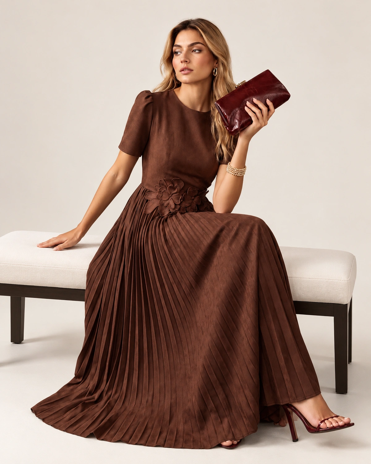 Vista posterior da modelo vestindo vestido midi em crepe plissado marrom com zíper dorsal.