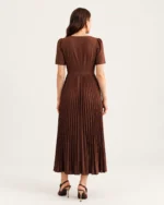 Editorial da modelo em estúdio mineral vestindo vestido midi em crepe plissado marrom.