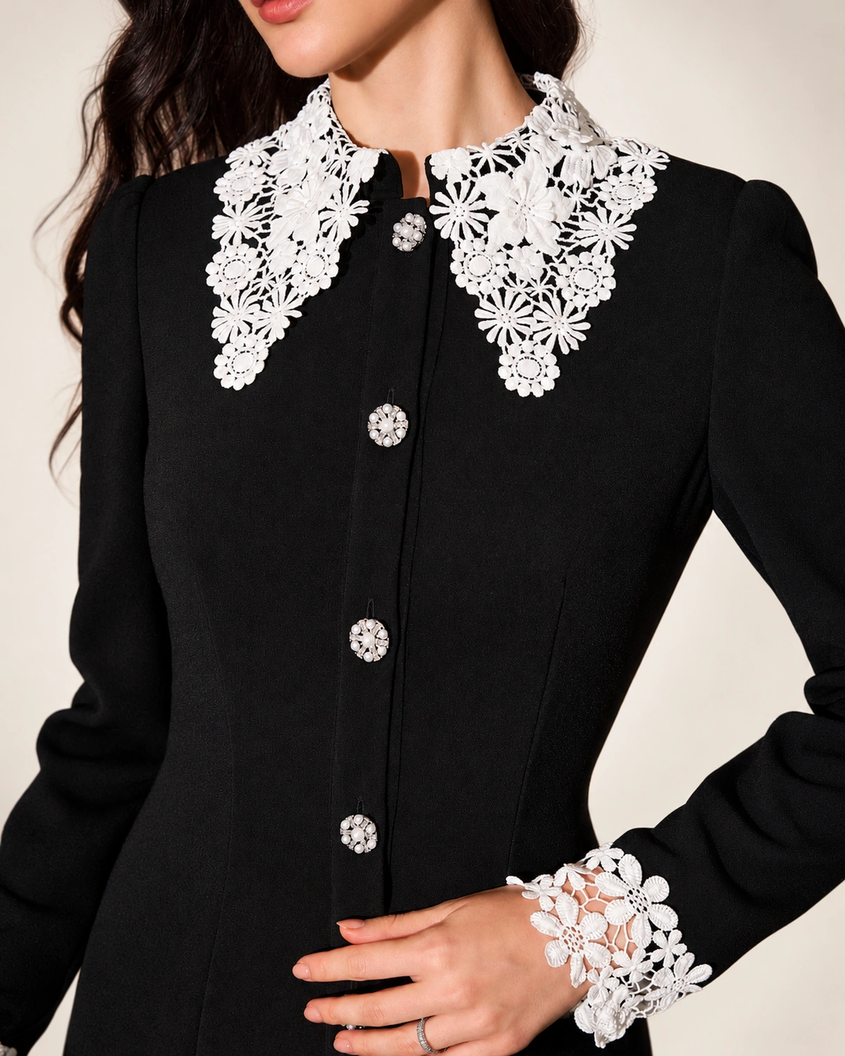 Modelo vestindo vestido midi evasê preto com gola e punhos de renda branca em estúdio mineral