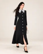 Modelo vestindo vestido midi evasê preto com gola e punhos de renda branca em estúdio mineral