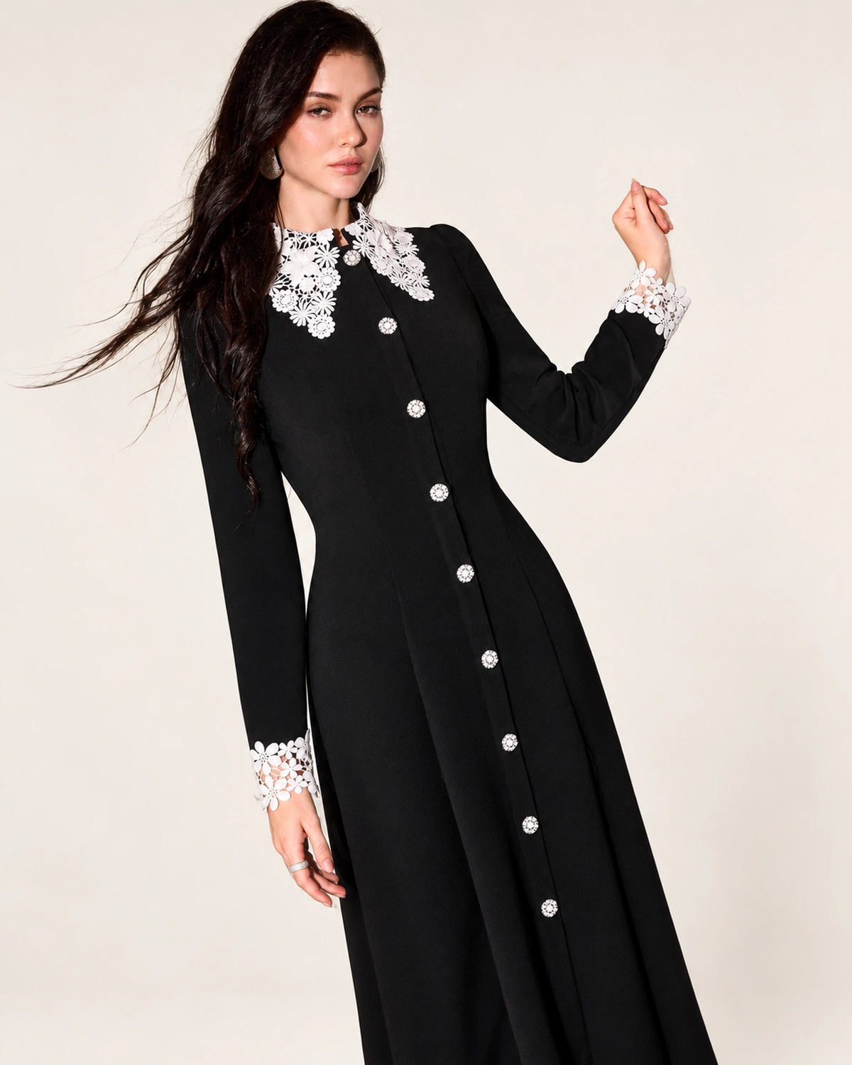 Modelo vestindo vestido midi evasê preto com gola e punhos de renda branca em estúdio mineral