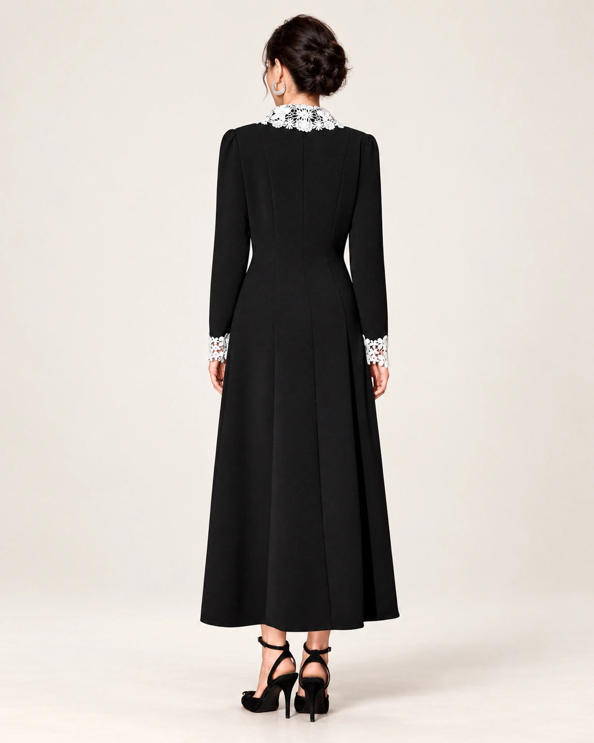 Modelo vestindo vestido midi evasê preto com gola e punhos de renda branca em estúdio mineral