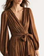Macro do decote V transpassado e faixa de amarração em chiffon plissado bronze em estúdio mineral