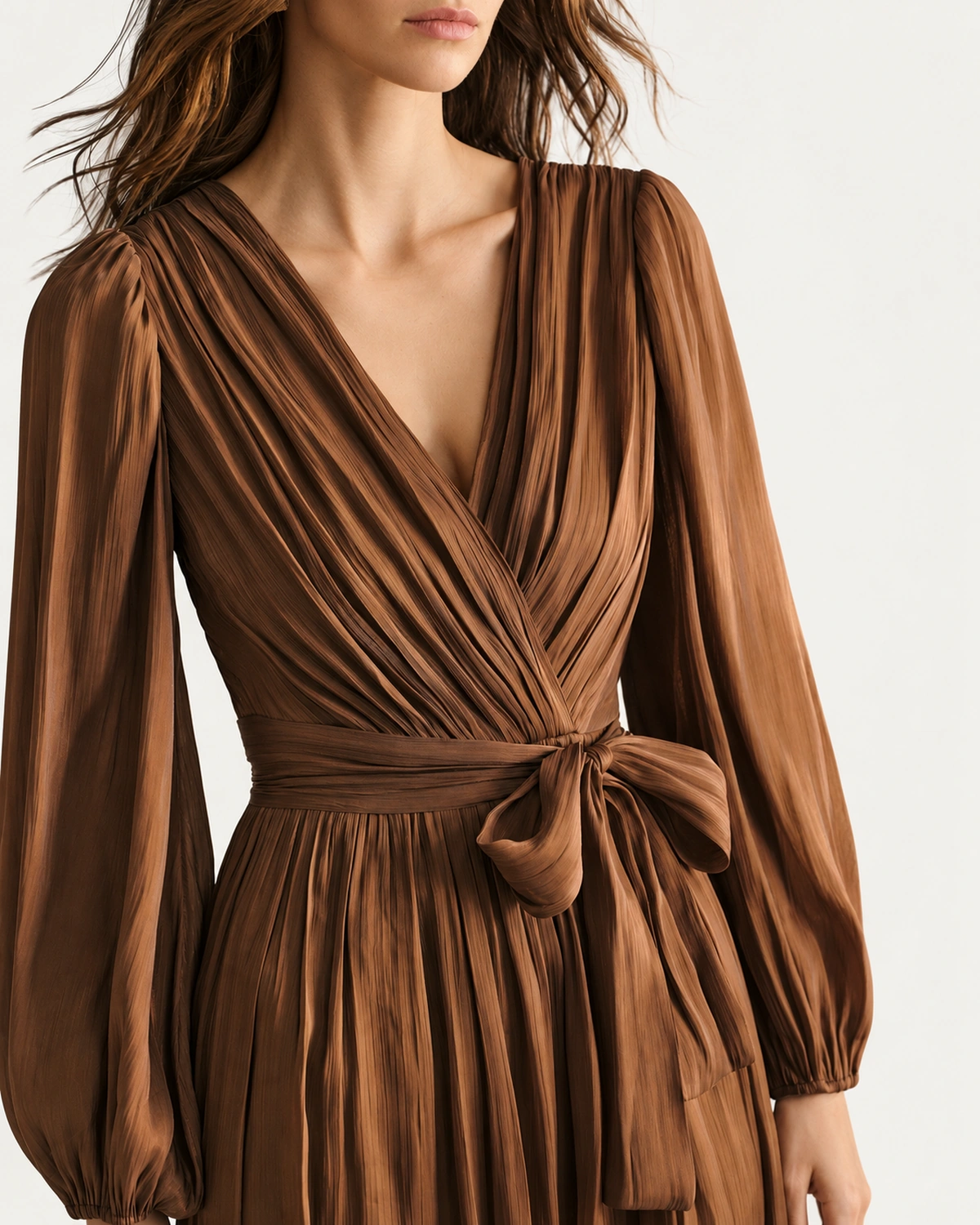 Macro do decote V transpassado e faixa de amarração em chiffon plissado bronze em estúdio mineral