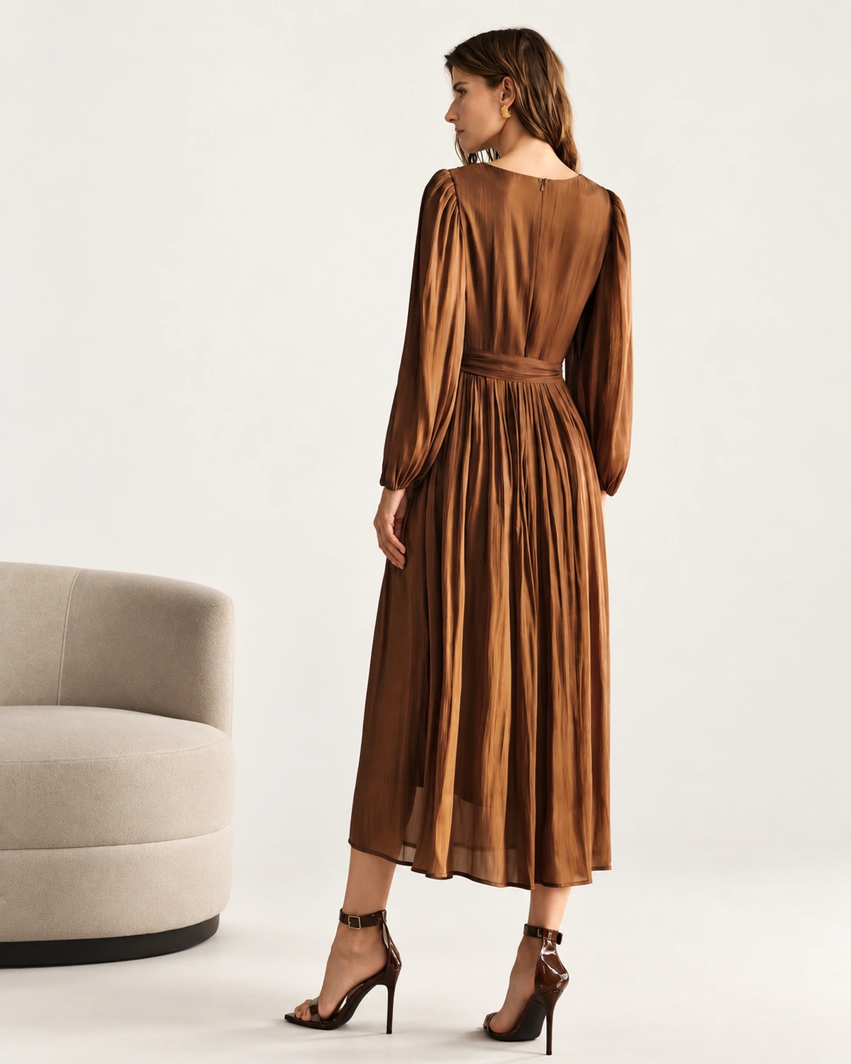 Vista posterior da modelo vestindo vestido midi plissado bronze em estúdio mineral