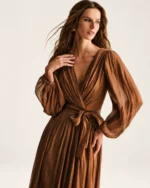 Plano médio destacando a leveza das mangas bispo em chiffon plissado bronze em estúdio mineral