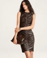 Plano americano da modelo vestindo vestido em couro marrom com clutch em estúdio mineral